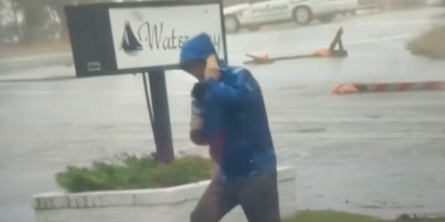 Ρεπόρτερ μάχεται με τον τυφώνα Φλόρενς ενώ πίσω του άλλοι περπατούν χαλαροί