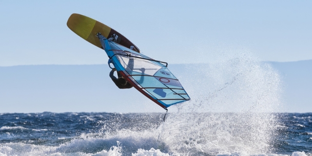 Young Windsurfer Jumping Wave on Windsurf Board