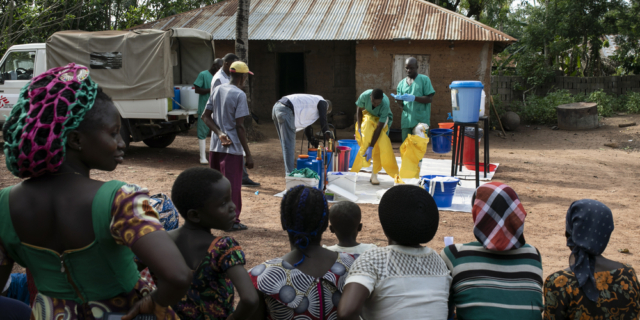 Kάτοικοι παρακολουθούν την διαδικασία απολύμανσης ενός σπιτιού στο χωριό Ndiovu, αφού ένας κάτοικος διαγνώστηκε με τον πυρετό Lassa.