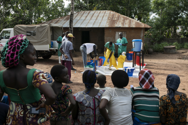 Kάτοικοι παρακολουθούν την διαδικασία απολύμανσης ενός σπιτιού στο χωριό Ndiovu, αφού ένας κάτοικος διαγνώστηκε με τον πυρετό Lassa.