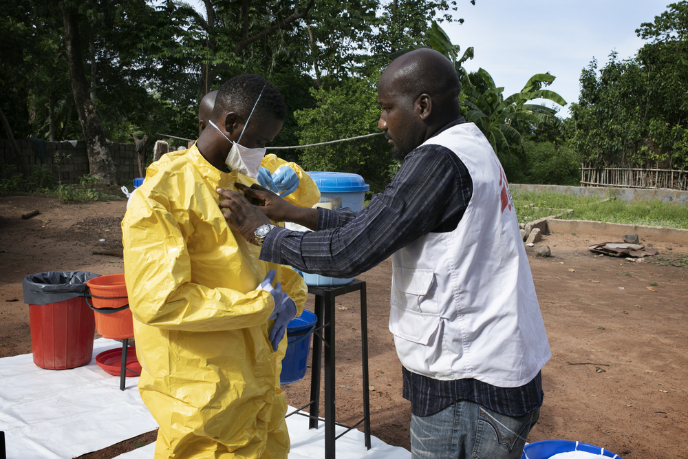 Μετά τη διάγνωση του πυρετού Lassa σε έναν κάτοικο του χωριού Ndiovu, μια ομάδα επισκέπτεται το χωριό για να απολυμάνει το σπίτι του ασθενούς. Ο επικεφαλής της ομάδας Gilkenny Okonkwo βοηθά το προσωπικό να φορέσει σωστά τον απαραίτητο εξοπλισμό.
