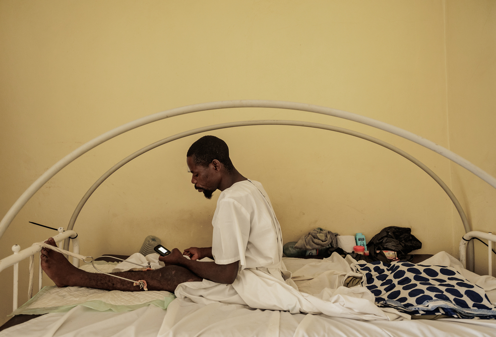 Ένας ασθενής χρησιμοποιεί το τηλέφωνό του, ενώ αναρρώνει μετά από επιτυχημένη χειρουργική επέμβαση από την ομάδα των Γιατρών Χωρίς Σύνορα στην Bunia.