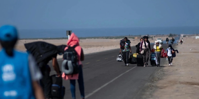 Μια οικογένεια από τη Βενεζουέλα περπατάει στον αυτοκινητόδρομο που βρίσκεται παράλληλα στο σύνορο με τη Χιλή στις 3 Δεκεμβρίου 2021 στην νότια περιοχή Tacna του Περού.