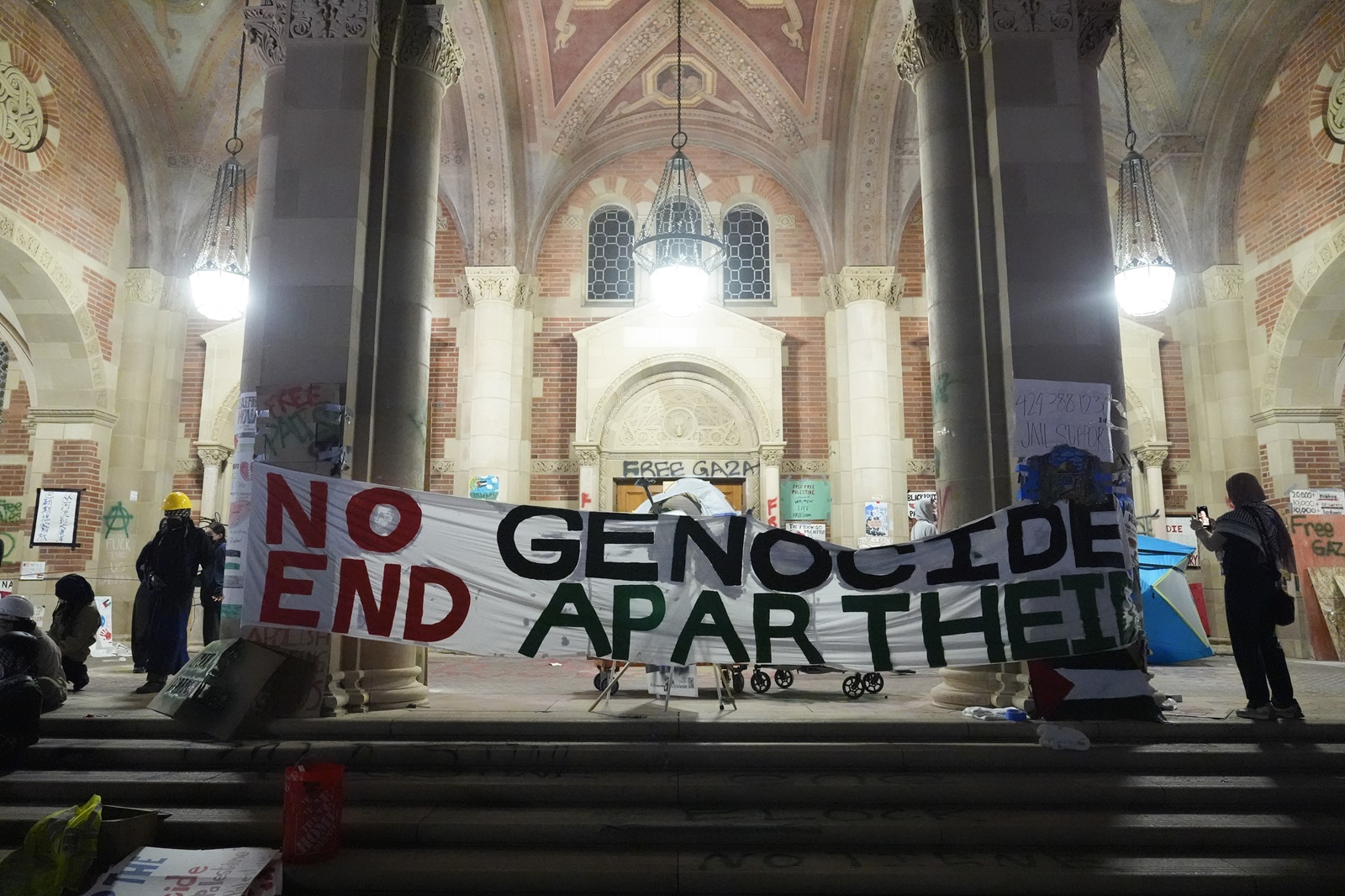 Διαδηλωτές στο πανεπιστήμιο της Καλιφόρνια κρατούν πανό που χαρακτηρίζει ως γενοκτονία τον πόλεμο στη Γάζα