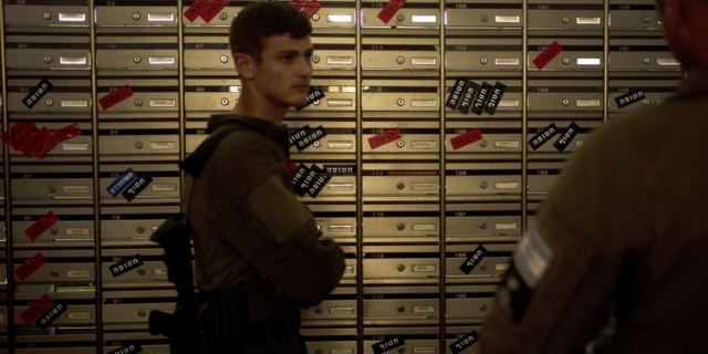 Ισραηλινοί στρατιώτες επισκέπτονται την αίθουσα αλληλογραφίας στο Κιμπούτς Νιρ Οζ, όπου στα γραμματοκιβώτια αναγράφεται η κατάσταση των κατοίκων σκοτώθηκαν (κόκκινο), απήχθησαν (μαύρο) και αφέθηκαν ελεύθεροι (μπλε)