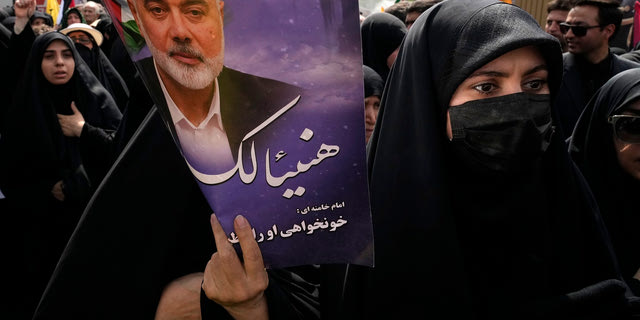 Γυναίκα κρατά αφίσα του Ισμαήλ Χανίγια στην Τεχεράνη