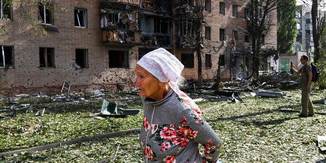 Μια ηλικιωμένη γυναίκα περπατάει μπροστά από ένα κτίριο που έχει υποστεί ζημιές μετά από βομβαρδισμό στην ουκρανική πλευρά του Κουρσκ,