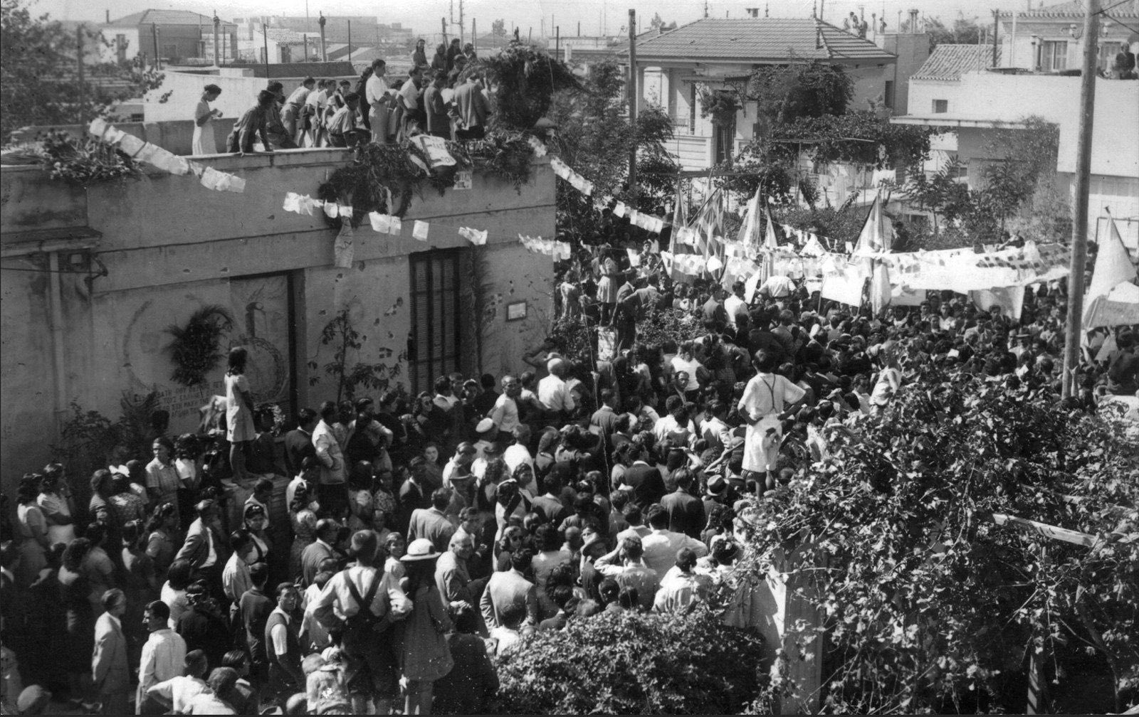 Καλλιθέα, 24 Ιουλίου 1945. Πλήθος κόσμου συμμετέχει στο ετήσιο μνημόσυνο έξω από το σπίτι της οδού Μπιζανίου 10 όπου οχυρώθηκαν οι 10 άνδρες του ΕΛΑΣ κατά τη διάρκεια της μάχης της Καλλιθέας