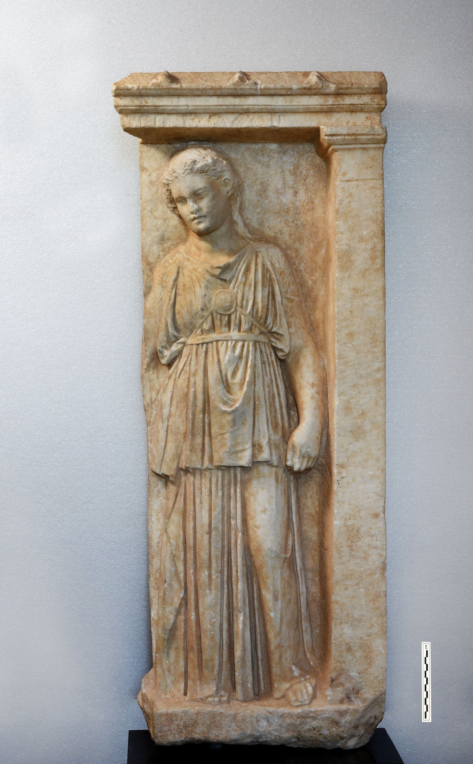 Τμήμα αττικού επιτύμβιου ναΐσκου από πεντελικό μάρμαρο, ύψους 0,95μ. και πλάτους 0,42μ. με ανάγλυφη παράσταση