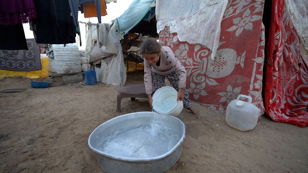 Η Layan, 11 ετών, ρίχνει νερό σε ένα μεγάλο μπολ για να πλύνει τα ρούχα της οικογένειάς της.