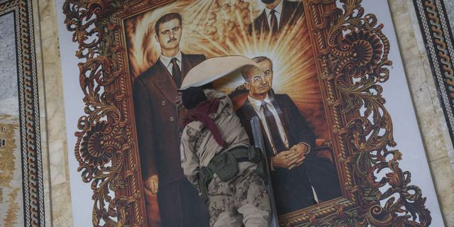 Αντάρτης σκίζει αφίσα του προέδρου της Συρίας Μπασάρ Άσαντ και του εκλιπόντα πατέρα του Χαζέφ Άσαντ