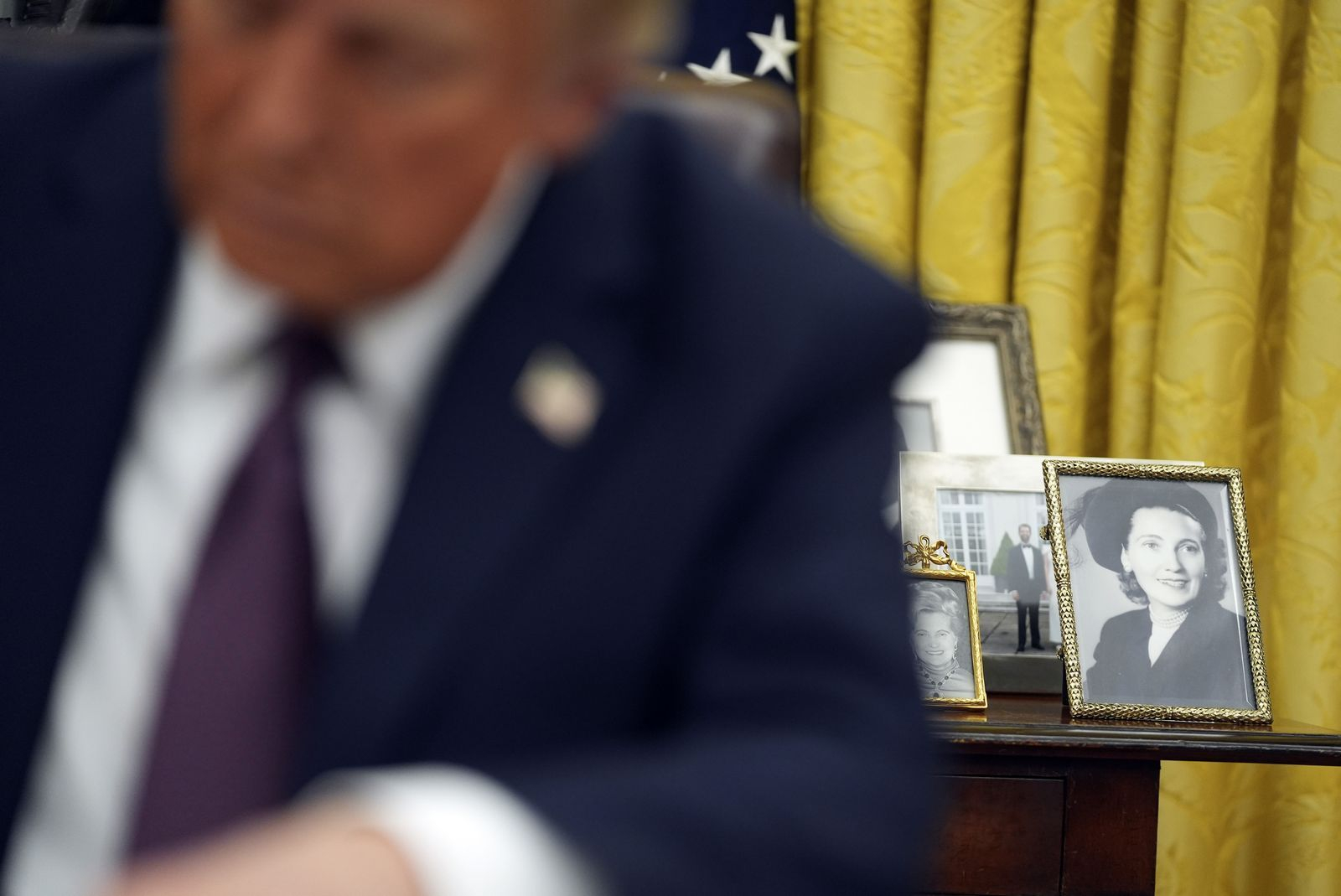 Οικογενειακές φωτογραφίες φαίνονται στο φόντο καθώς ο πρόεδρος Ντόναλντ Τραμπ υπογράφει εκτελεστικά διατάγματα στο Οβάλ Γραφείο του Λευκού Οίκου