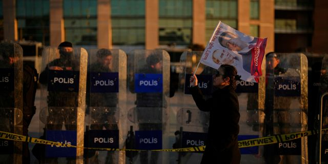 Ένας διαδηλωτής περνά μπροστά από τις δυνάμεις αντιμετώπισης ταραχών έξω από το δικαστήριο Τσαγλαγιάν κατά τη διάρκεια διαμαρτυρίας ενάντια στη σύλληψη του Δημάρχου της Κωνσταντινούπολης, Εκρέμ Ιμάμογλου