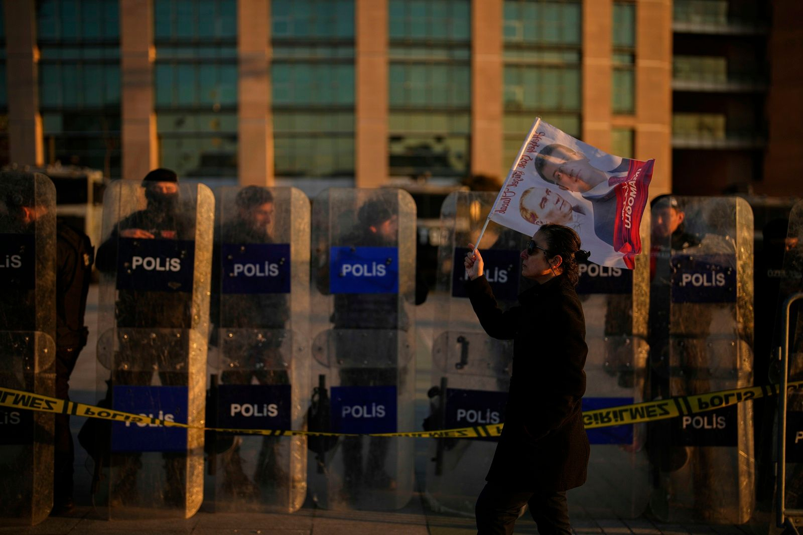 Ένας διαδηλωτής περνά μπροστά από τις δυνάμεις αντιμετώπισης ταραχών έξω από το δικαστήριο Τσαγλαγιάν κατά τη διάρκεια διαμαρτυρίας ενάντια στη σύλληψη του Δημάρχου της Κωνσταντινούπολης, Εκρέμ Ιμάμογλου