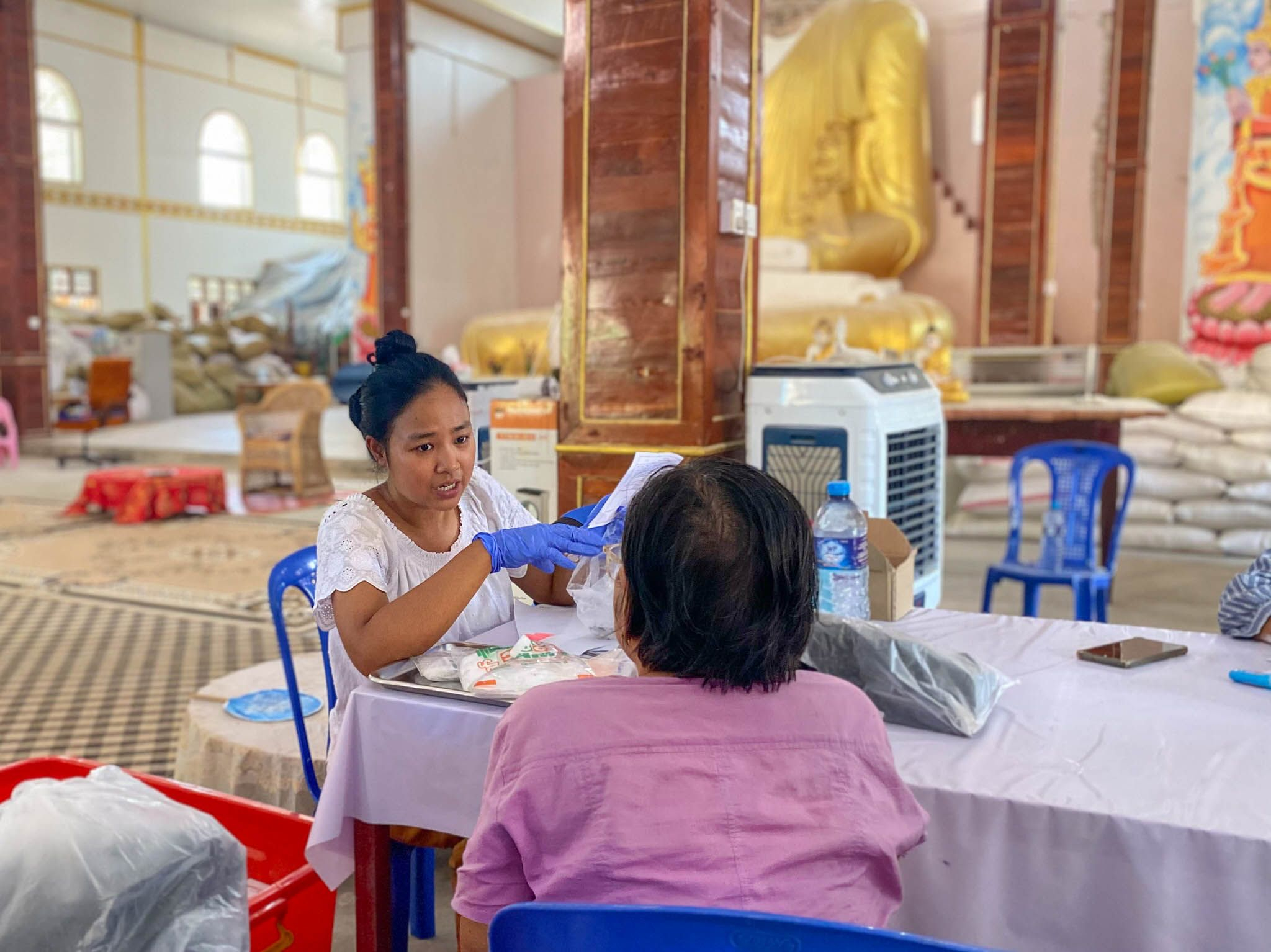 Μια ασθενής λαμβάνει φάρμακα στην κινητή κλινική των Γιατρών Χωρίς Σύνορα που έχει δημιουργηθεί μέσα σε ένα μοναστήρι, το οποίο σήμερα φιλοξενεί περίπου 80 οικογένειες από τη γειτονιά των οποίων τα σπίτια έχουν καταστραφεί ή έχουν υποστεί σοβαρές ζημιές και δεν είναι πλέον ασφαλή να ζουν. Μιανμάρ, Απρίλιος 2025.
