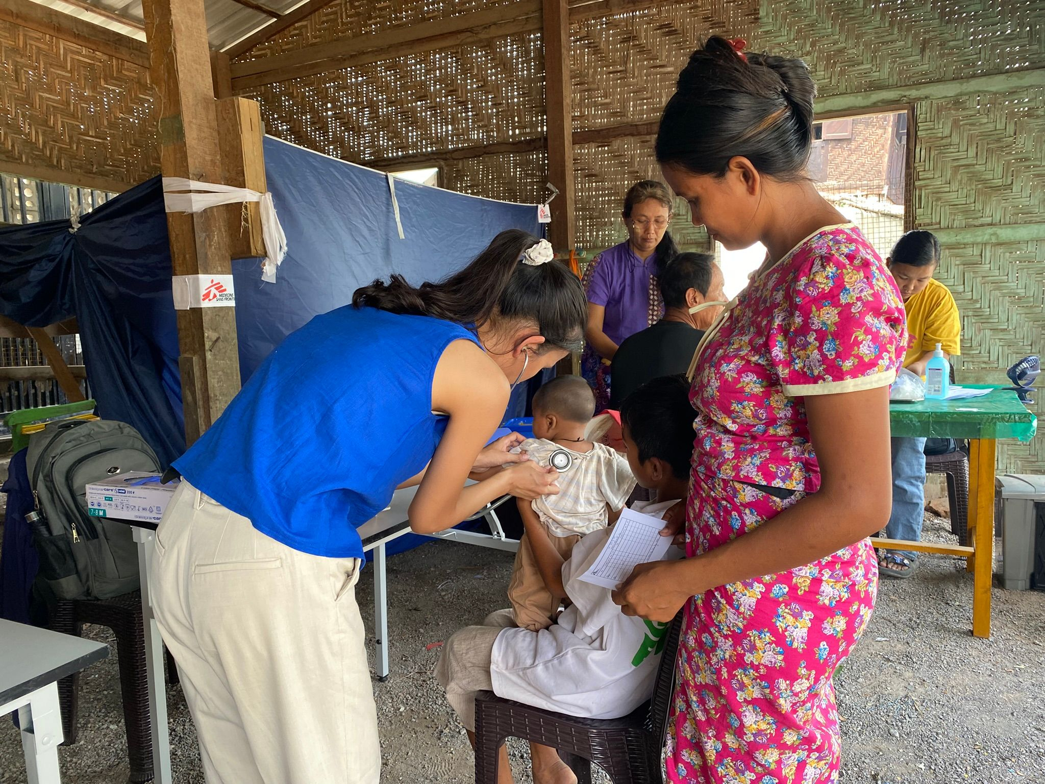 H Dr. Zar Zar Lin Aung εξετάζει τον Kaung Pyae Khant (4 μηνών), ο οποίος έχει βήχα. Ο αδελφός του, Kaung Pyae Kyaw (13 ετών) τον κρατά αγκαλιά, ενώ η μητέρα του Zin Mar Win (30 ετών) παραμένει κοντά του.