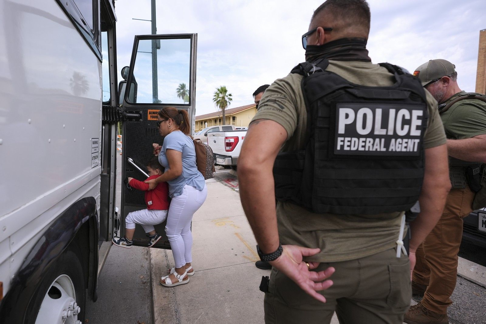 Μια γυναίκα και τα παιδιά της επιβιβάζονται σε λεωφορείο μετά τη σύλληψή τους