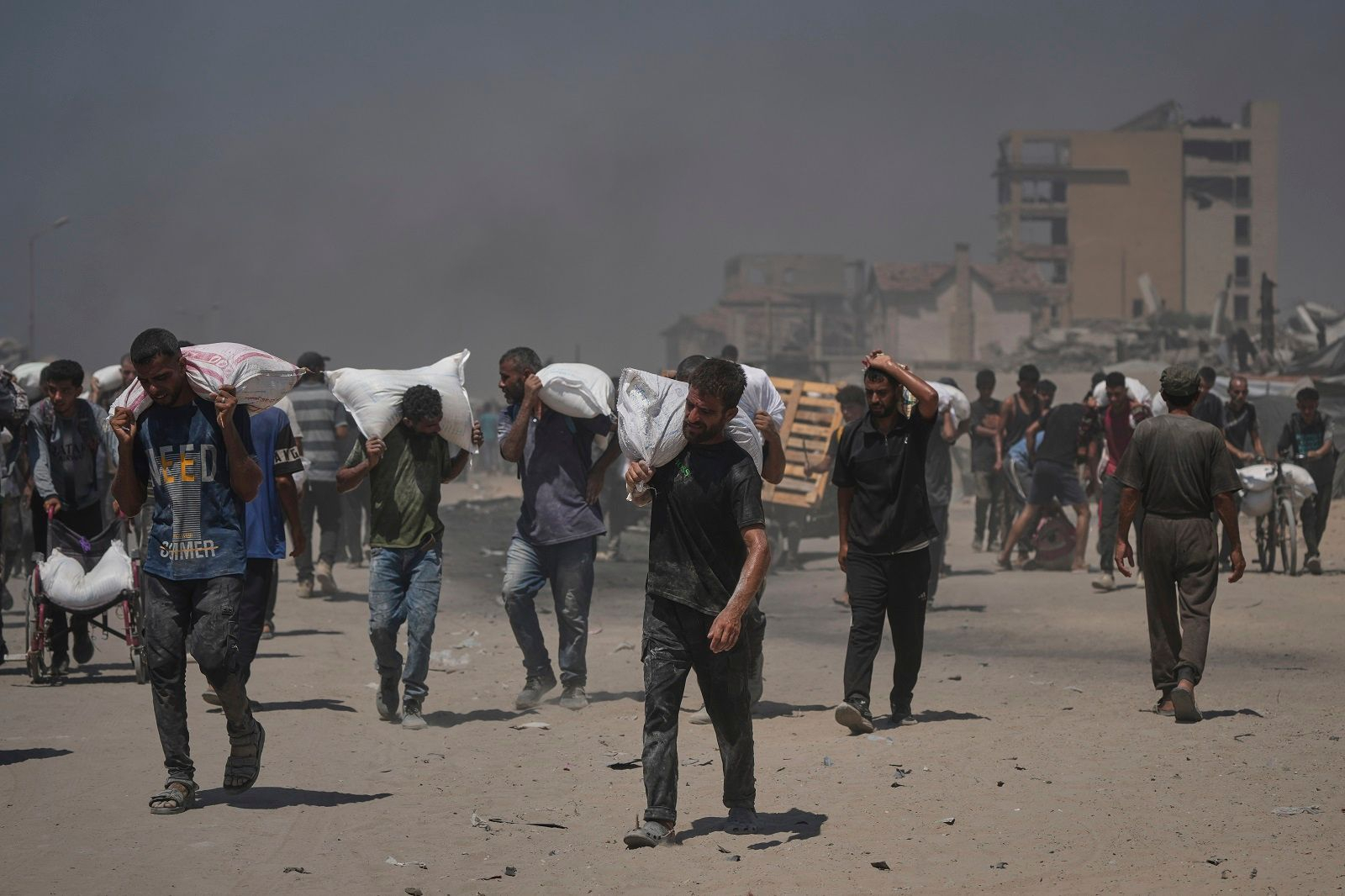 Παλαιστίνιοι στη Γάζα κουβαλούν σακιά με ανθρωπιστική βοήθεια, 27/7/2025