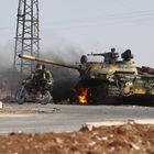 Στρατιώτες των κυβερνητικών δυνάμεων της Συρίας περνούν δίπλα από φλεγόμενο τανκ στα περίχωρα της Σουέιντα