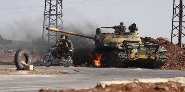 Στρατιώτες των κυβερνητικών δυνάμεων της Συρίας περνούν δίπλα από φλεγόμενο τανκ στα περίχωρα της Σουέιντα