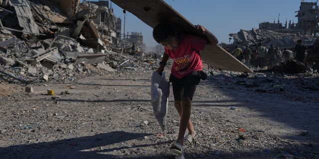 Ένα παιδί που έχει εκτοπιστεί, κουβαλά ένα κομμάτι ξύλου, στην κατεστραμμένη από τους βομβαρδισμούς πόλη της Γάζας