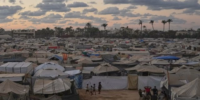 Ομάδα Παλαιστινίων κάθεται έξω από μια σκηνή σε έναν προσωρινό καταυλισμό στο Ντέιρ αλ-Μπάλαχ, στην κεντρική Λωρίδα της Γάζας