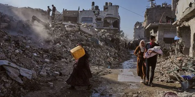 Παλαιστίνιοι περπατούν ανάμεσα στα χαλάσματα που έχουν αφήσει πίσω τους οι σαρωτικοί βομβαρδισμοί του Ισραήλ στη Γάζα