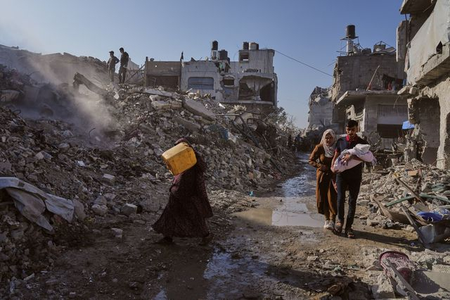 Παλαιστίνιοι περπατούν ανάμεσα στα χαλάσματα που έχουν αφήσει πίσω τους οι σαρωτικοί βομβαρδισμοί του Ισραήλ στη Γάζα
