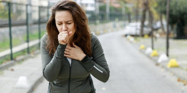 Γυναίκα που γυμνάζεται βήχει λόγω ατμοσφαιρικής ρύπανσης