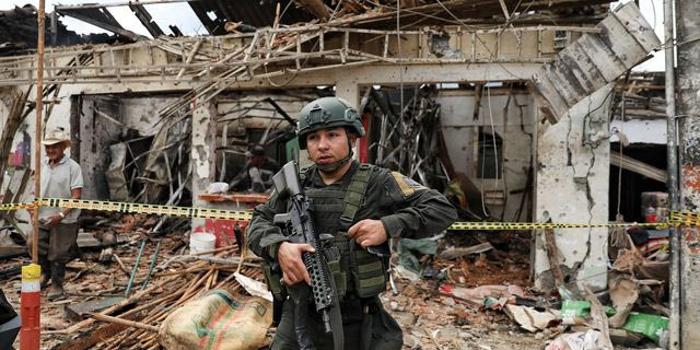 Αστυνομικός στέκεται μπροστά από ένα κτίριο που υπέστη ζημιές σε επίθεση, την οποία ο στρατός αποδίδει σε αποστάτες των αποστρατευμένων Επαναστατικών Ένοπλων Δυνάμεων της Κολομβίας