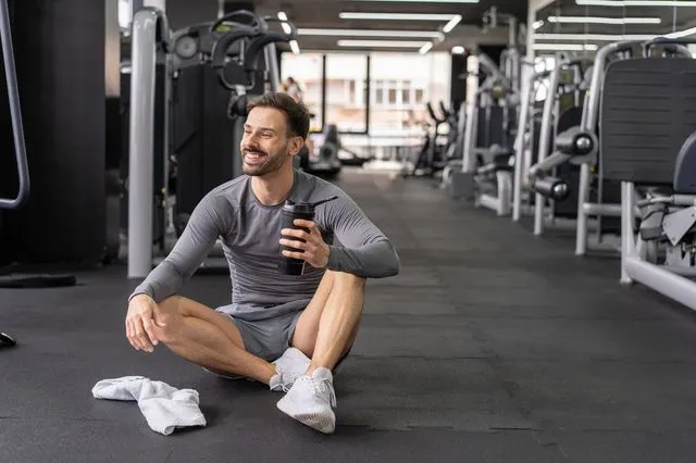 Άνδρας καταναλώνει πρωτεΐνη εν μέσω της προπόνησης