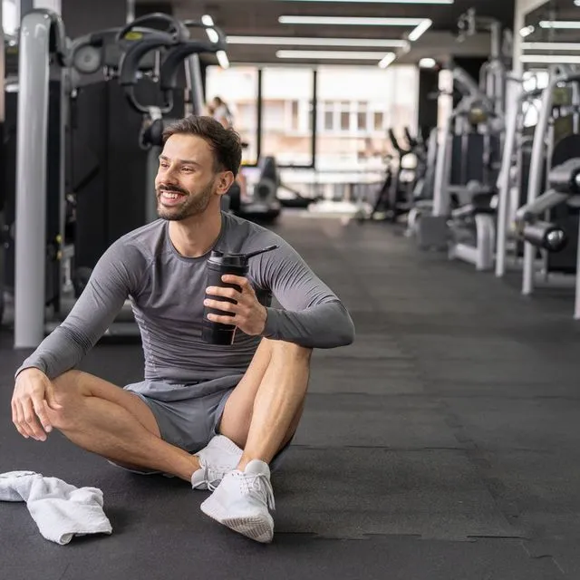 Άνδρας καταναλώνει πρωτεΐνη εν μέσω της προπόνησης
