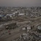 Παλαιστίνιοι περνούν δίπλα από ένα κατεστραμμένο ισραηλινό τεθωρακισμένο όχημα, μέσα σε εκτεταμένη καταστροφή στη Γάζα (αρχείο)