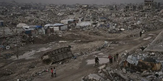 Παλαιστίνιοι περνούν δίπλα από ένα κατεστραμμένο ισραηλινό τεθωρακισμένο όχημα, μέσα σε εκτεταμένη καταστροφή στη Γάζα (αρχείο)