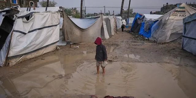 Ένας μικρός Παλαιστίνιος περπατά σε μια περιοχή σε προσωρινό καταυλισμό σκηνών μετά από έντονες βροχοπτώσεις στο Ντέιρ αλ-Μπάλαχ, στην κεντρική Λωρίδα της Γάζας, την Παρασκευή 12 Δεκεμβρίου 2025