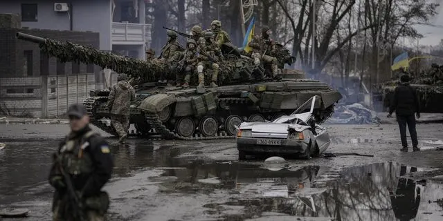 Ουκρανικό τανκ περνά δίπλα από ένα κατεστραμμένο αμάξι έξω από το Κίεβο, όπου πραγματοποιήθηκαν μάχες μεταξύ Ρώσων και Ουκρανών