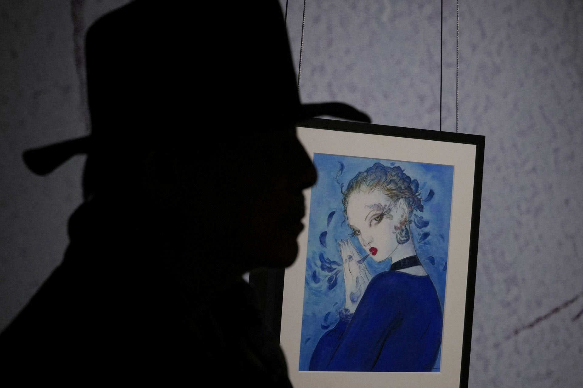 Η σιλουέτα του Yoshitaka Amano μπροστά από έναν πίνακά του