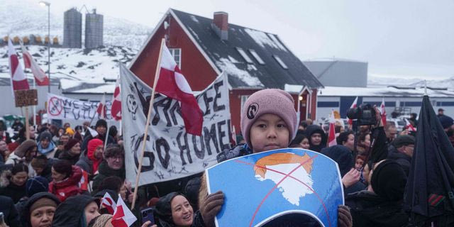 Ένα αγόρι κρατά μια εικόνα με διαγραμμένο χάρτη της Γροιλανδίας που πάνω του έχει μια περούκα που συμβολίζει τον Τραμπ, στη διαδήλωση μπροστά από το αμερικανικό προξενείο στο Νουούκ της Γροιλανδίας