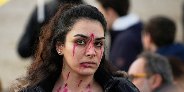 Διαδηλώτρια με βαφή στο πρόσωπο για να αναπαραστήσει τις σφαίρες