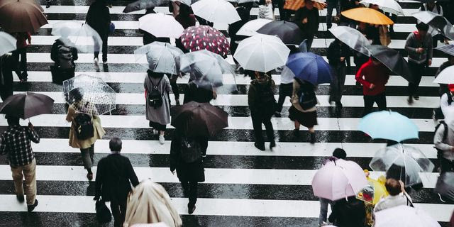Κόσμος σε διασταύρωση κρατώντας ομπρέλες