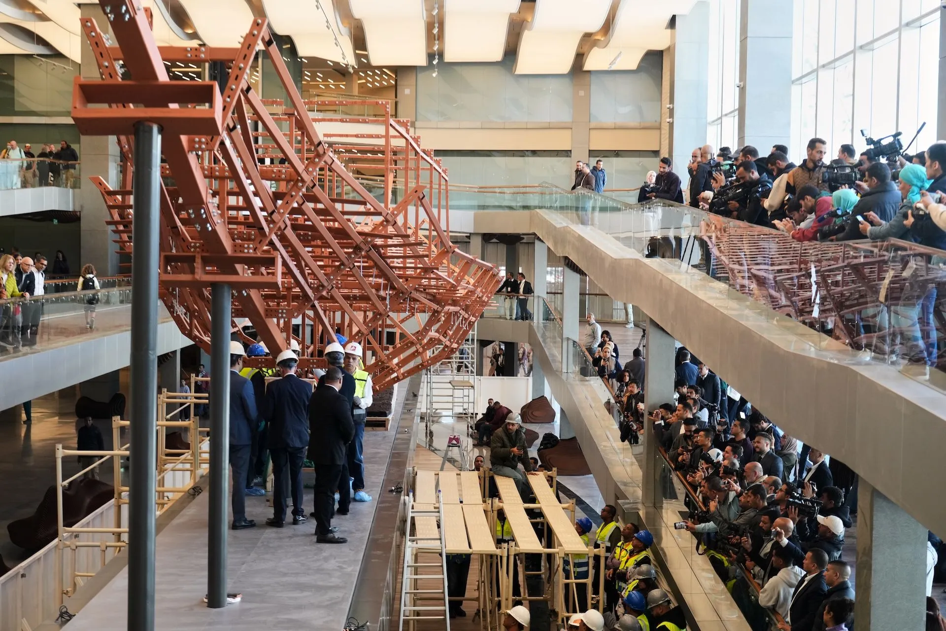 Οι άνθρωποι βιντεοσκοπούν αρχαιολόγους καθώς επανασυναρμολογούν τη δεύτερη ηλιακή βάρκα του βασιλιά Χέοπα, στο Μεγάλο Αιγυπτιακό Μουσείο στη Γκίζα της Αιγύπτου,