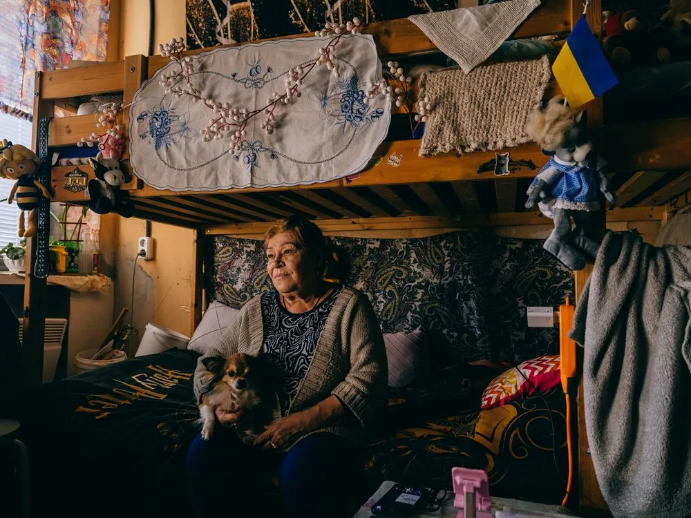 Η Zinaida Babisheva, 67 ετών, αγκαλιάζει τον σκύλο της, τον Toshyk. Εκκενώθηκε από το Lyman τον Μάρτιο του 2022, αφήνοντας πίσω της το σπίτι και τη γειτονιά που σημάδεψαν τη ζωή της.