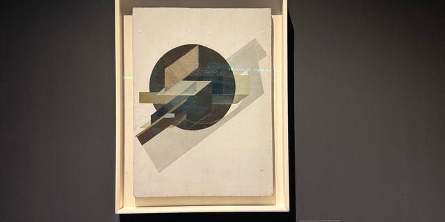 Γκούσταβ Κλούτσις [Ρουγιένα (Ρωσική Αυτοκρατορία, σημ. Λετονία) 1895 – εκτελέστηκε Μόσχα (ΕΣΣΔ, σημ. Ρωσία) 1938] Δυναμική πόλη, 1919 Λάδι, ξυρόδεμα και άμμος σε ξύλο, 87 × 63,5 εκ. MOMUS-Μουσείο Μοντέρνας Τέχνης-Συλλογή Κωστάκη Αρ. έργου 94.78