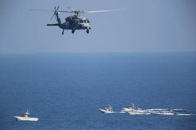 Αμερικανικό ελικόπτερο MH-60 Seahawk πετά πάνω από περιπολικά σκάφη των Φρουρών της Ισλαμικής Επανάστασης του Ιράν, στο Στενό του Ορμούζ (φωτογραφία αρχείου)