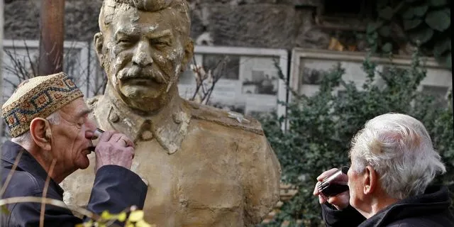 Δύο άνδρες πίνουν κρασί μπροστά από την προτομή του Στάλιν στην Τιφλίδα της Γεωργίας