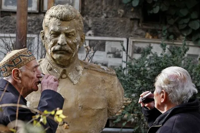 Δύο άνδρες πίνουν κρασί μπροστά από την προτομή του Στάλιν στην Τιφλίδα της Γεωργίας