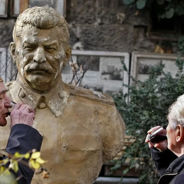 Δύο άνδρες πίνουν κρασί μπροστά από την προτομή του Στάλιν στην Τιφλίδα της Γεωργίας