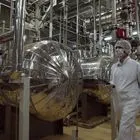 Ένας Ιρανός αξιωματούχος ασφαλείας με προστατευτική ενδυμασία περπατά μέσα από μέρος της Εγκατάστασης Μετατροπής Ουρανίου λίγο έξω από την πόλη Ισφαχάν