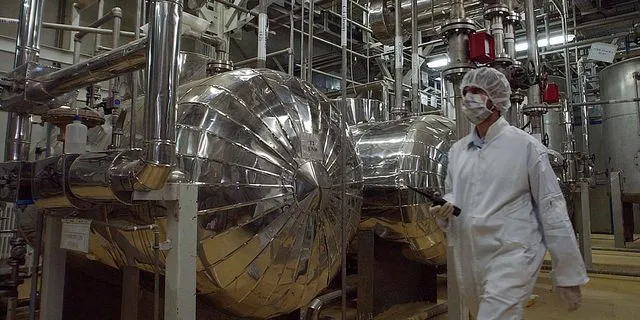 Ένας Ιρανός αξιωματούχος ασφαλείας με προστατευτική ενδυμασία περπατά μέσα από μέρος της Εγκατάστασης Μετατροπής Ουρανίου λίγο έξω από την πόλη Ισφαχάν