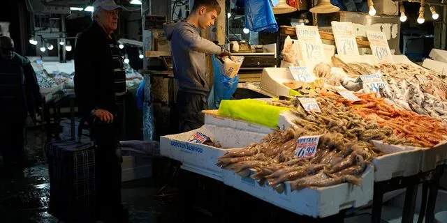 Ιχθυοπώλης τυλίγει ψάρια για έναν πελάτη στην Βαρβάκειο